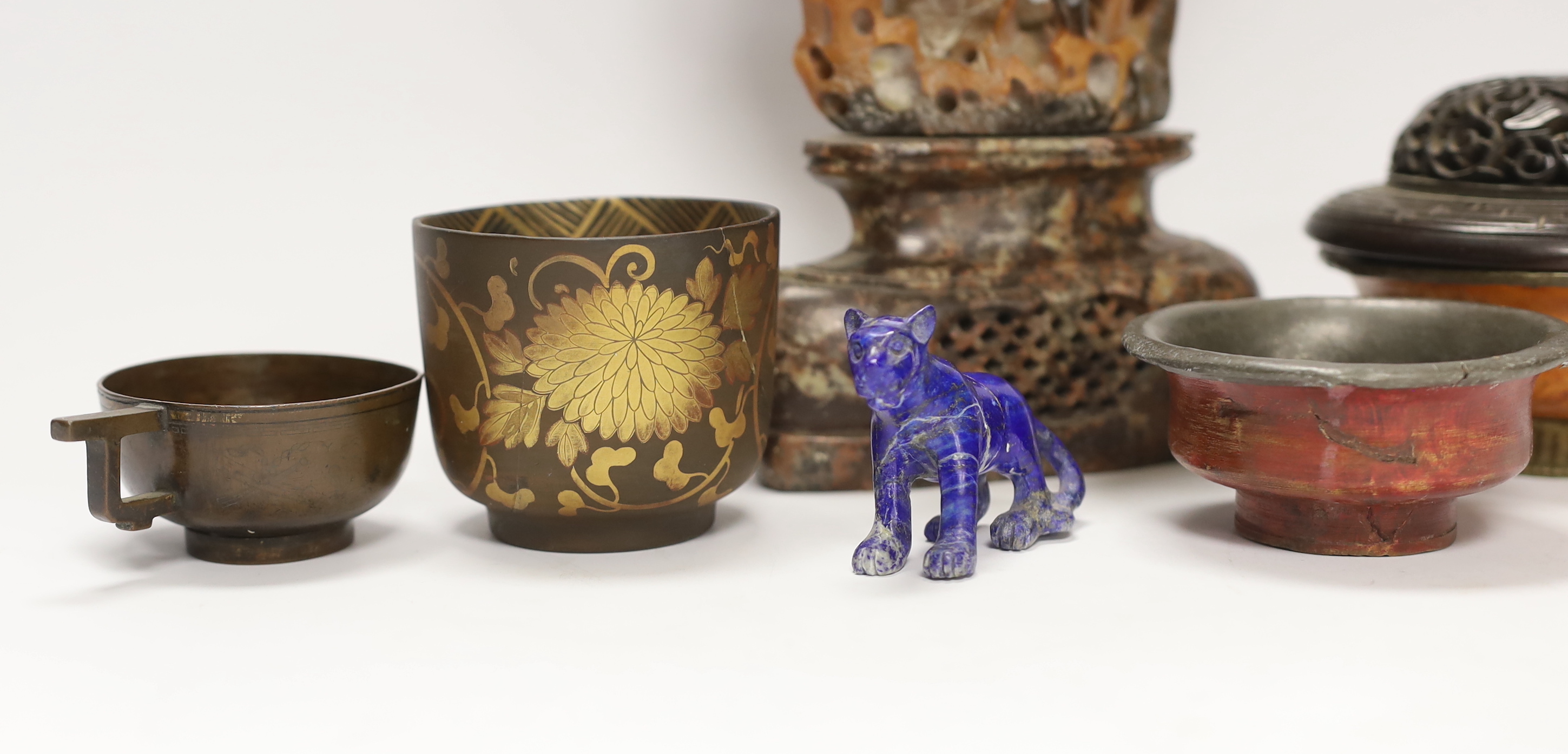 A Chinese carved hardwood cover, a soapstone carving, 27.5cm high, a lapis lazuli model of a tiger, a bronze teacup and two pewter and wood tea bowls (7)